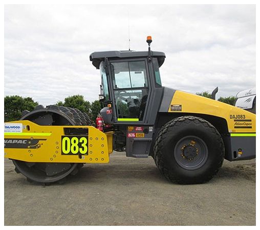 A yellow and black tractor with the number 083 on the side is parked on a dirt road.