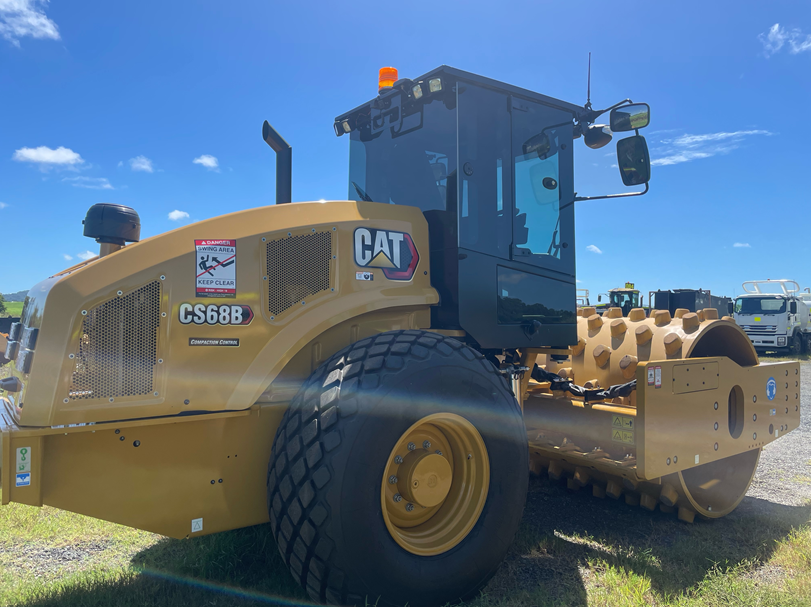 A cat roller is parked in a grassy field.