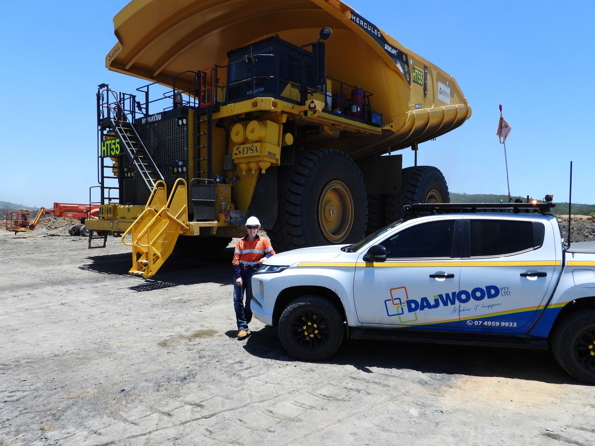 A black and yellow tractor is parked in a dirt field.
