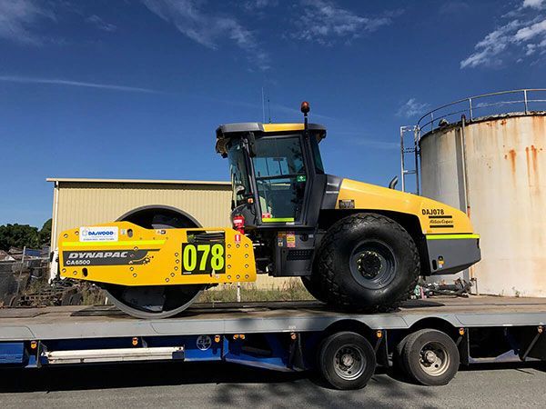 A yellow and black tractor is sitting on top of a trailer.