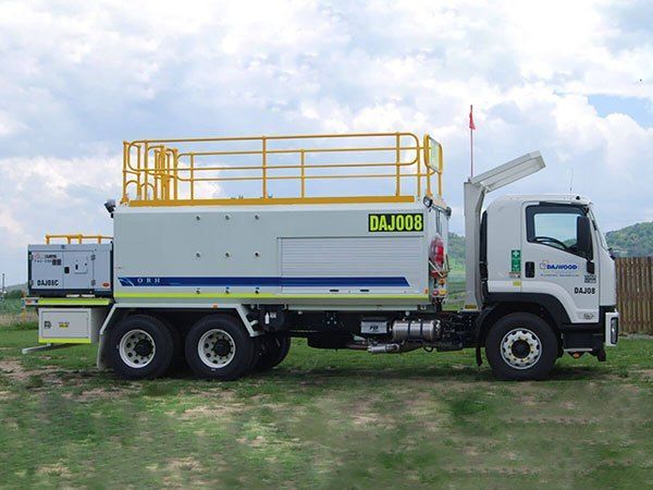 A white truck is parked in a grassy field.