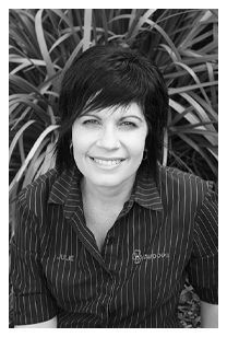 A woman in a striped shirt is smiling in a black and white photo.