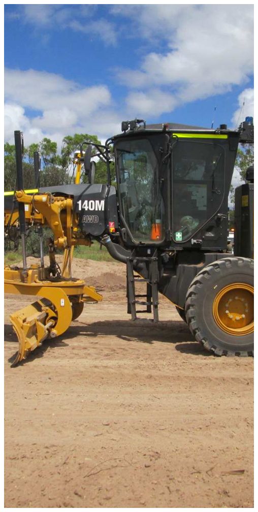 A black and yellow tractor is parked in a dirt field.