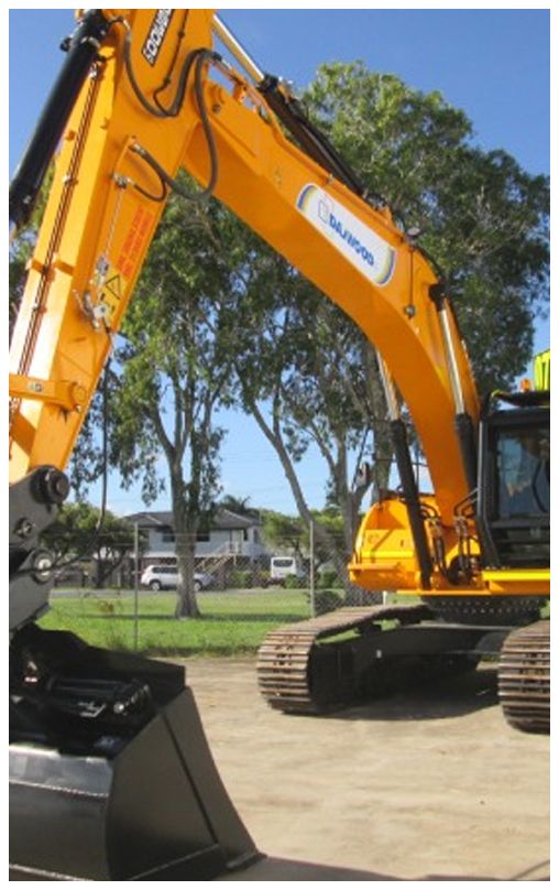 A large yellow excavator is parked in a parking lot