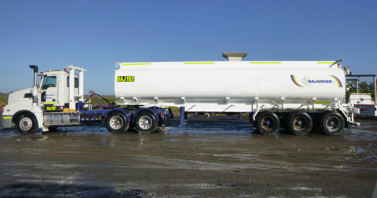 A white truck with a yellow railing is parked in a dirt field.