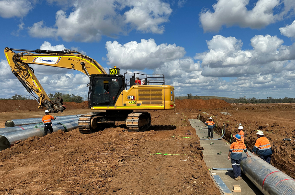 Two construction workers are sitting on a bulldozer at a construction site.