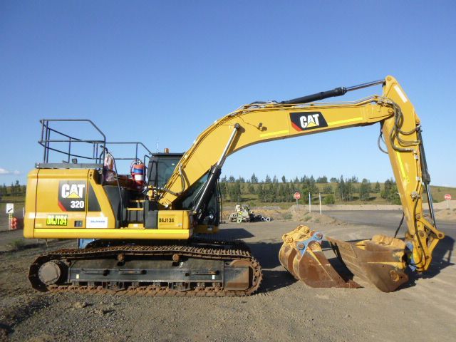 A yellow cat excavator is parked on a dirt road