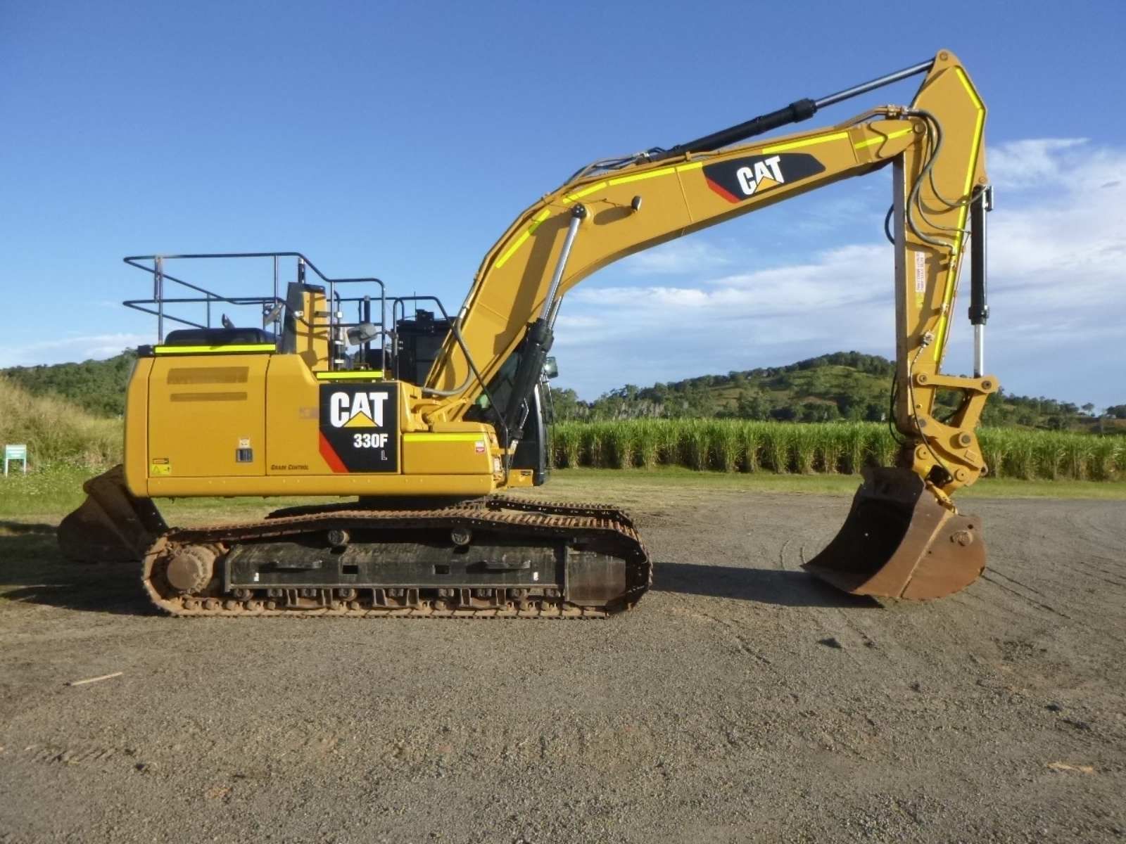 A yellow cat excavator is parked on a dirt road