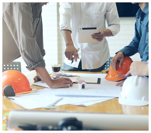 A group of men are sitting around a table looking at a blueprint.