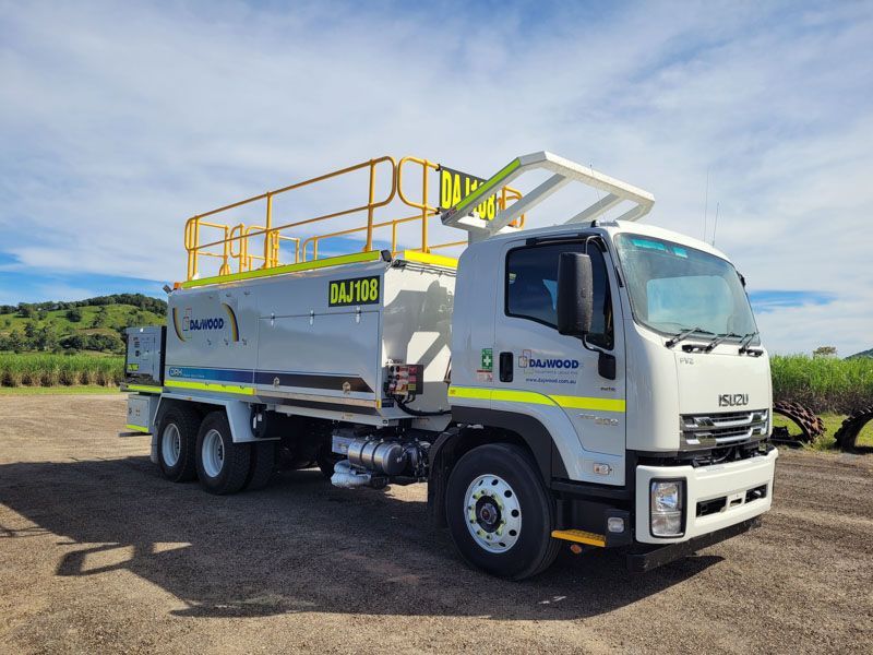 A white truck with a yellow railing is parked in a dirt lot.