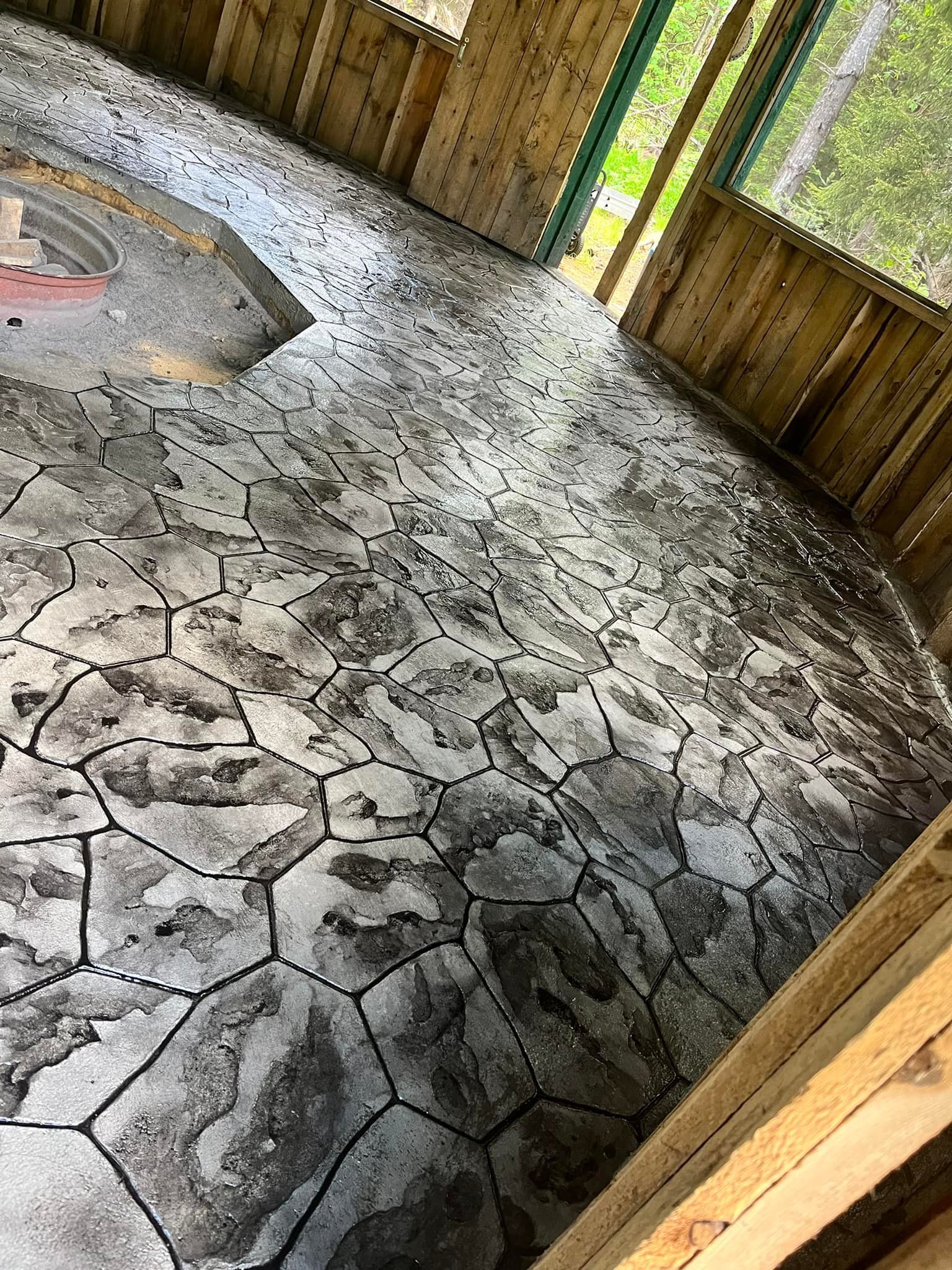 Stone patio with irregular gray paving and wooden fence, viewed inside a covered outdoor area