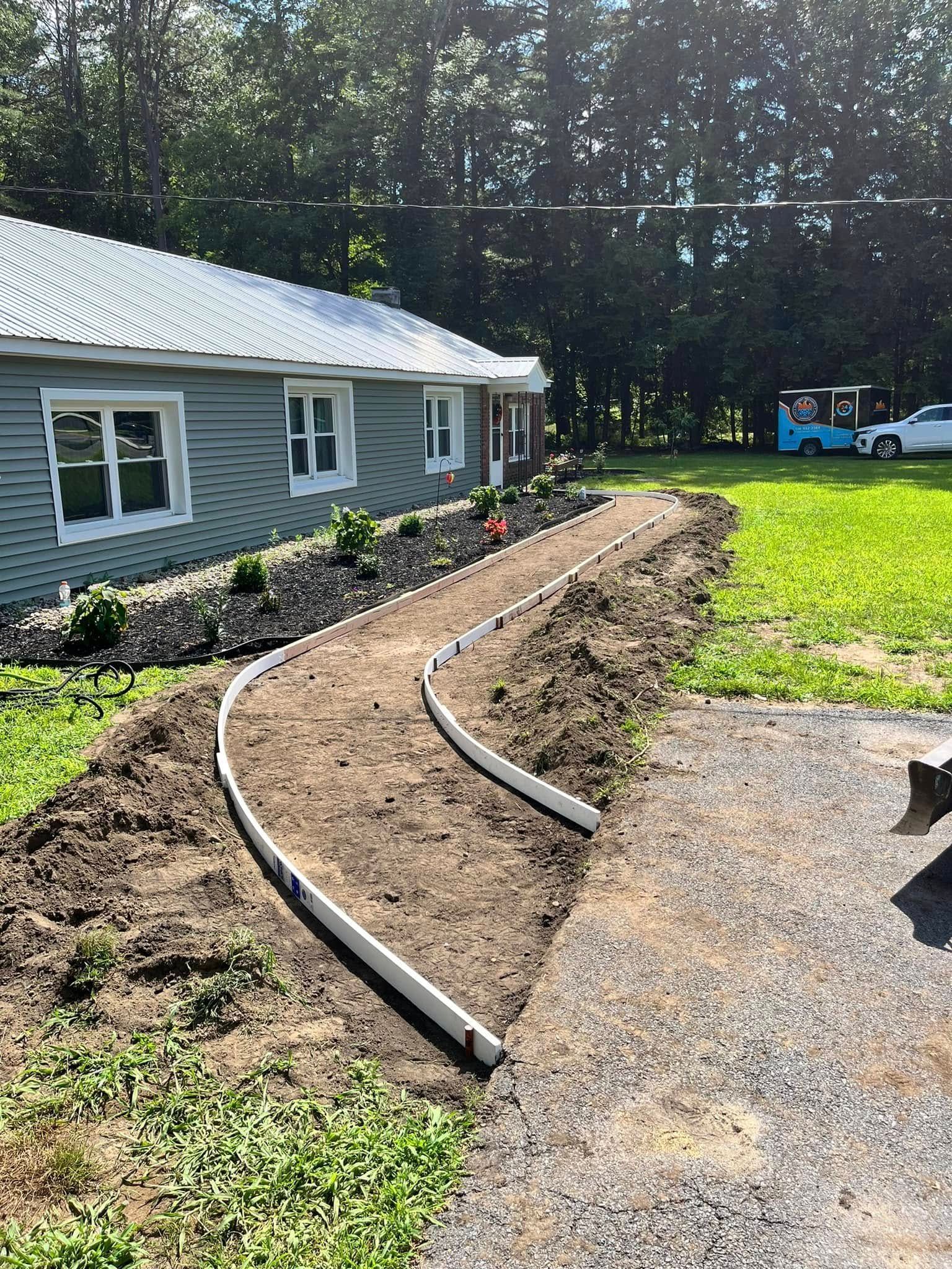Curved garden bed border along a house beside gravel driveway and green lawn