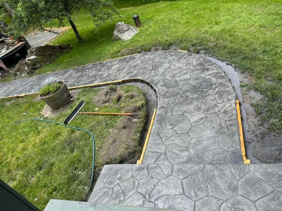 Stone path under construction in a grassy yard, with edging boards and tools nearby