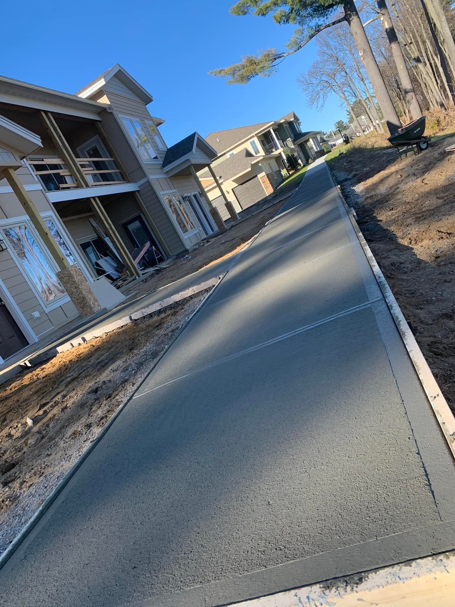 Fresh concrete walkway leading past new houses on a sunny day with clear blue sky.