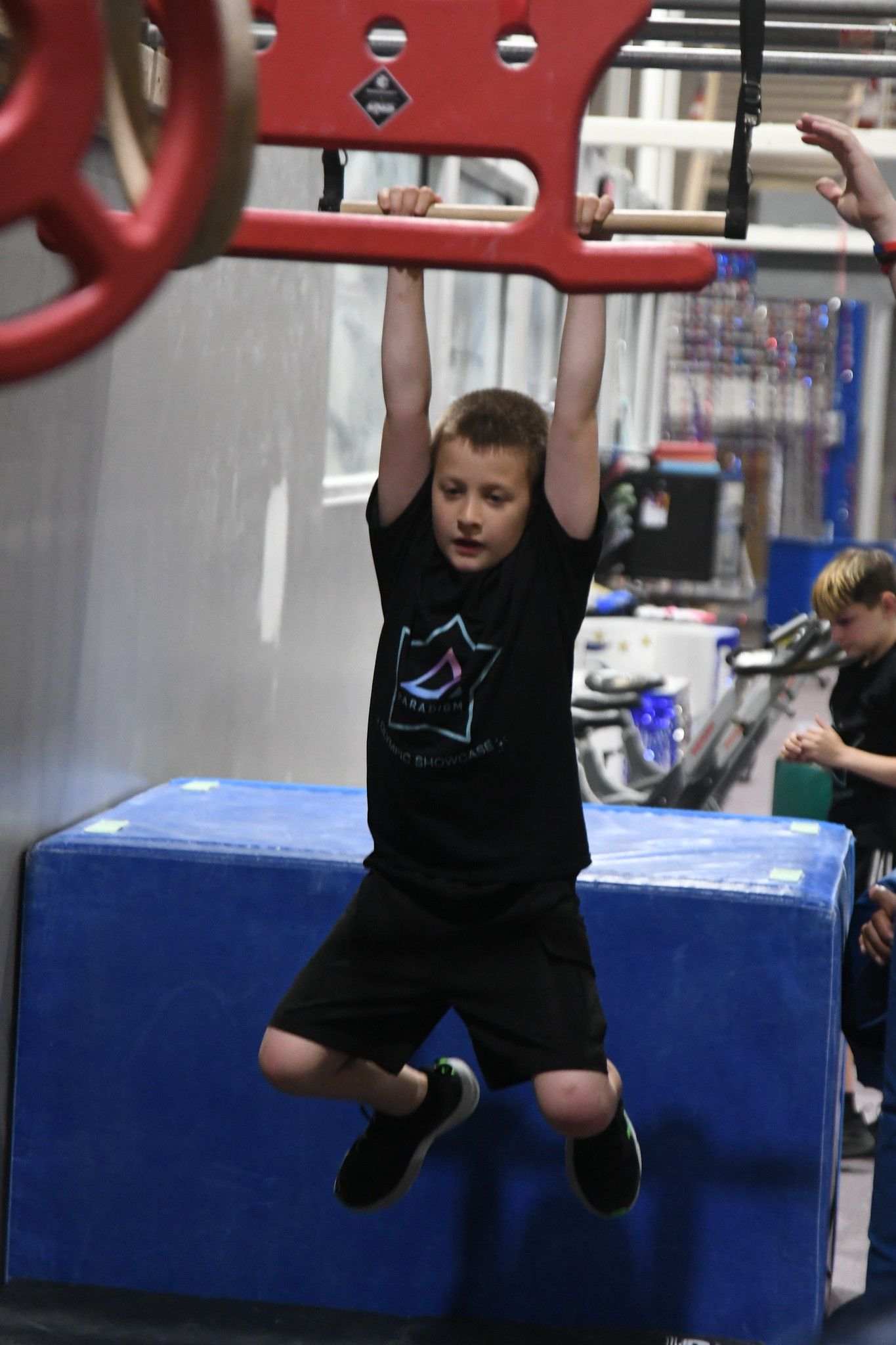 A young boy is climbing up a climbing wall.