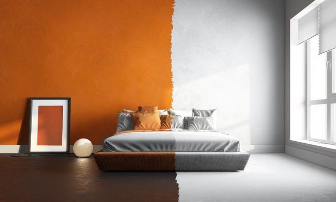 Modern bedroom with orange accent wall, gray bed, framed art, and large window