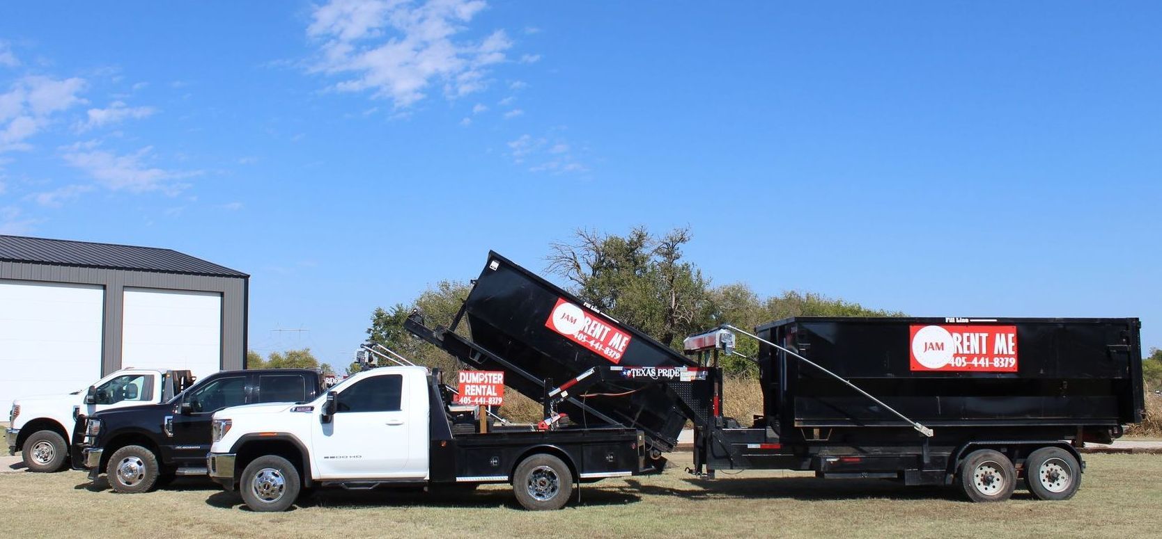 Two dump trucks are parked next to each other in a field.