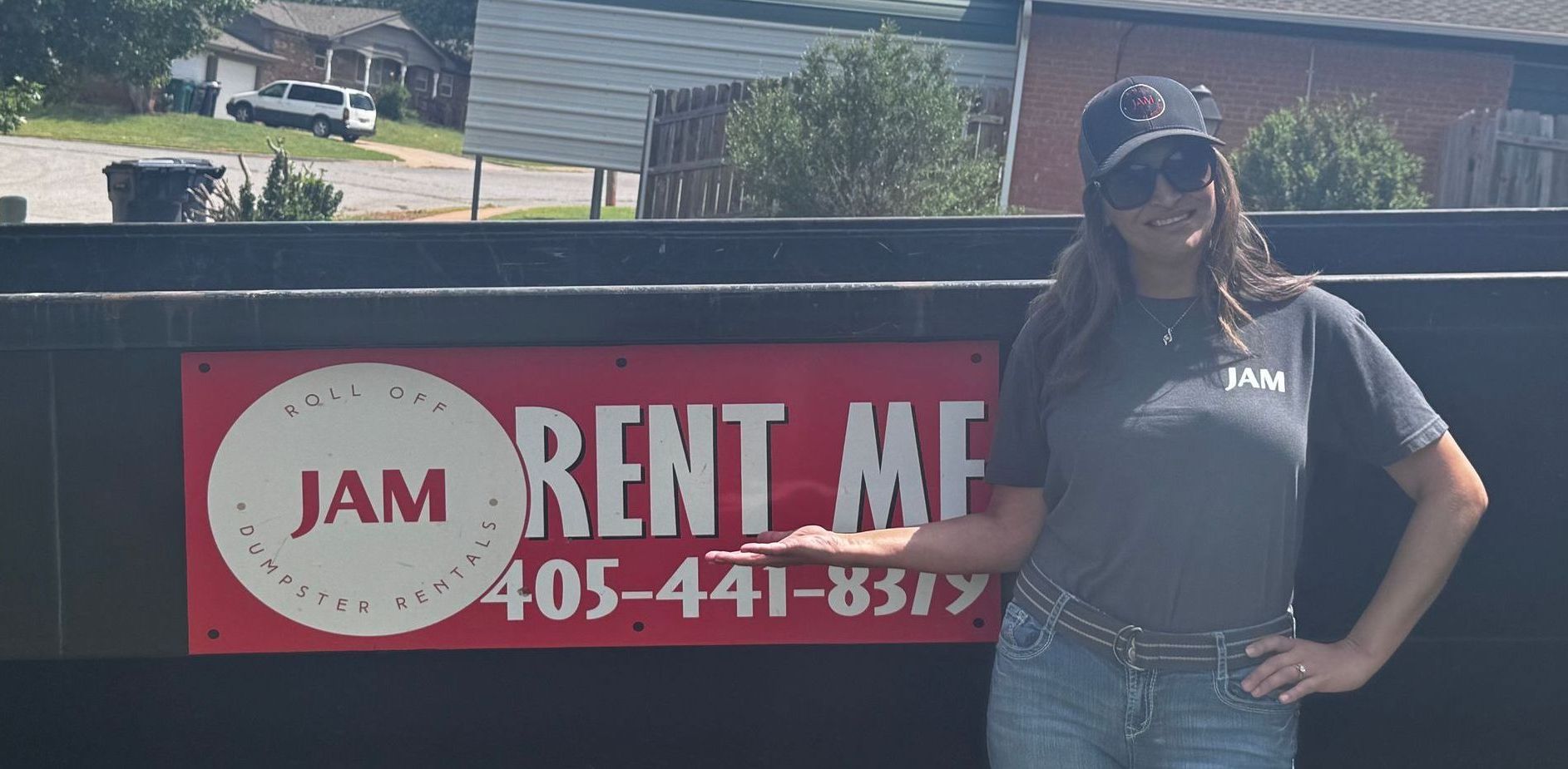 A woman is standing in front of a dumpster with a sign that says jam rent me.