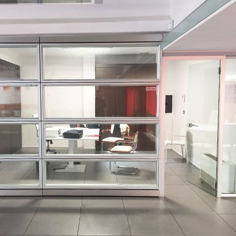 Una stanza con molte finestre, un tavolo e delle sedie.