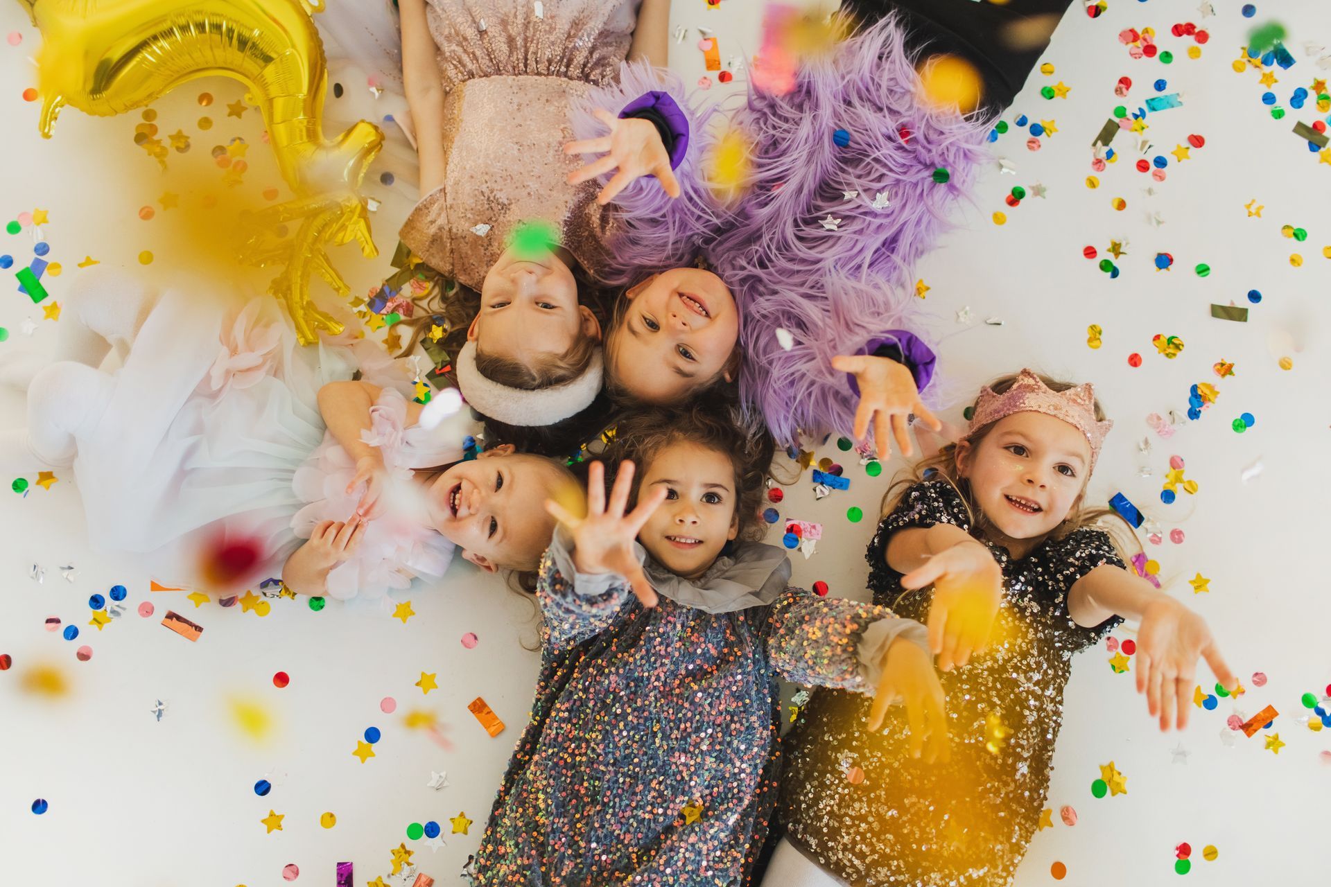 Un gruppo di bambine è sdraiato sul pavimento con coriandoli e palloncini.