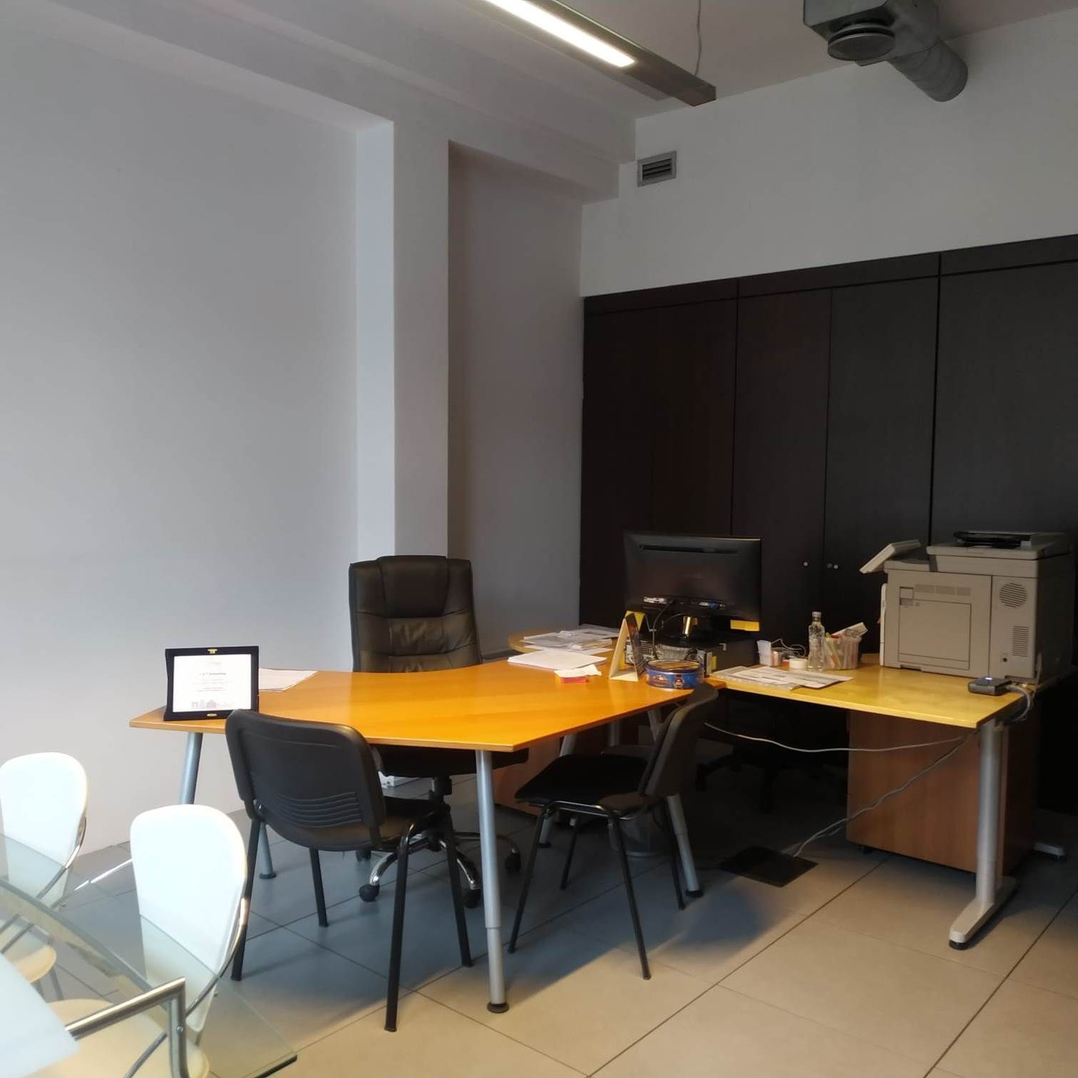 Un ufficio con una scrivania, sedie e una stampante