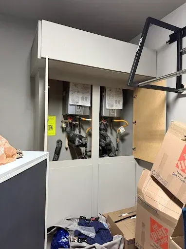 Small utility room with white cabinets, cardboard boxes, and gym equipment hanging overhead.