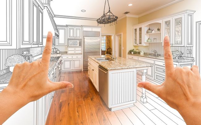 A person is framing a drawing of a kitchen with their hands.