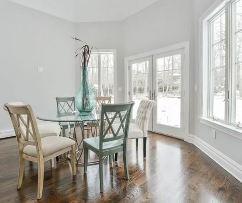 A dining room with a glass table and chairs and a vase on the table.