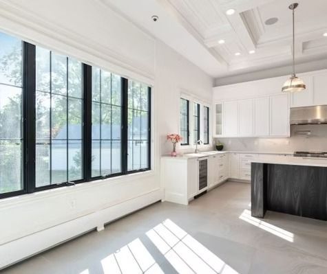 A kitchen with white cabinets and black windows and a black island.