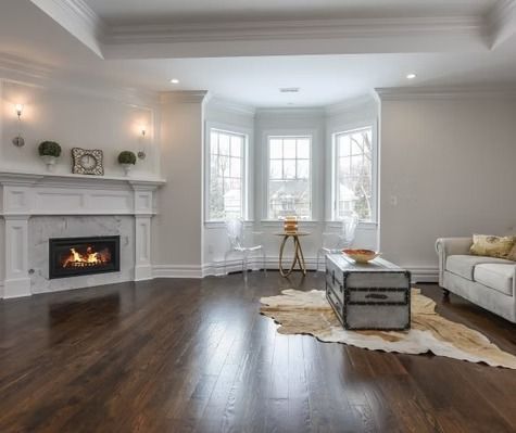 A living room with hardwood floors , a fireplace , a couch , and a coffee table.