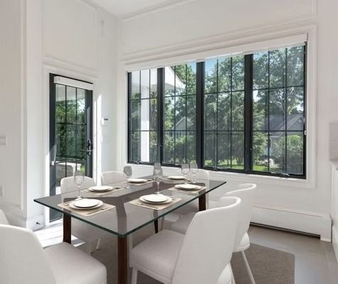 A dining room with a table and chairs and a lot of windows