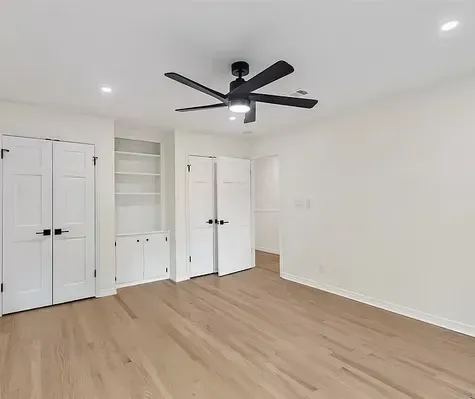 An empty room with hardwood floors and a ceiling fan.