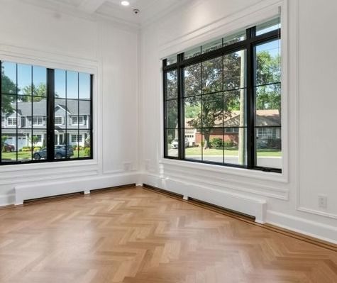 An empty room with a wooden floor and two windows.