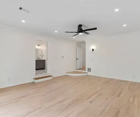 An empty living room with hardwood floors and a ceiling fan.