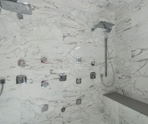 A shower with a marble wall and a shower head.