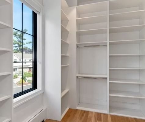 A walk in closet with lots of shelves and a window.