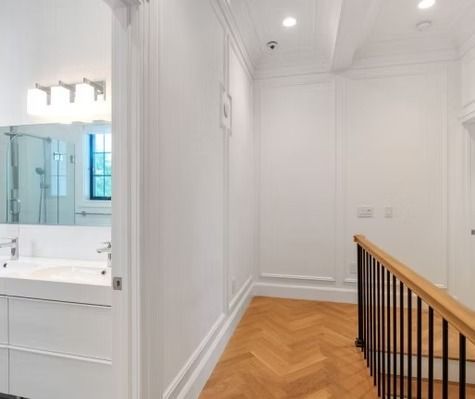 A hallway leading to a bathroom with a sink and stairs