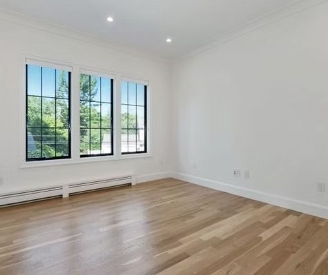An empty room with hardwood floors and three windows.