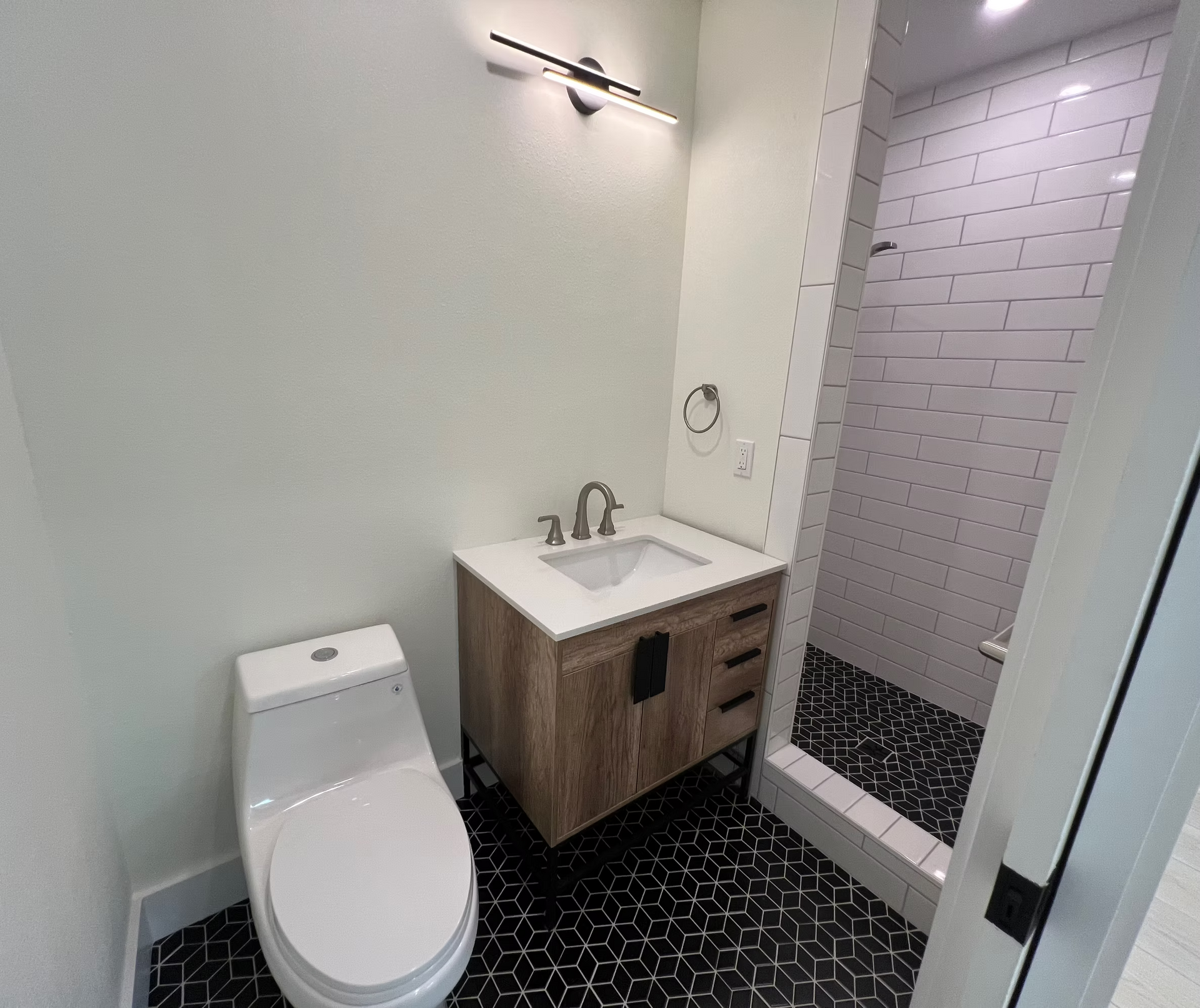 A bathroom with a toilet , sink and shower.