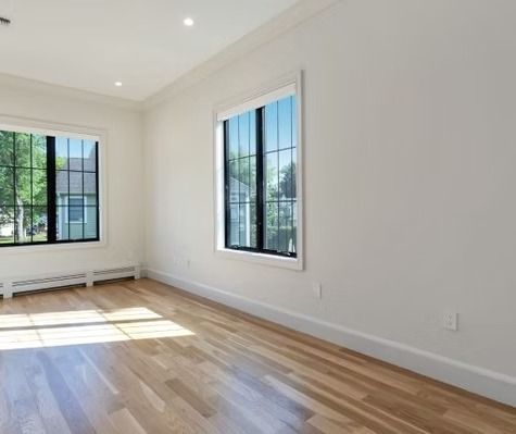 An empty room with hardwood floors and two windows.