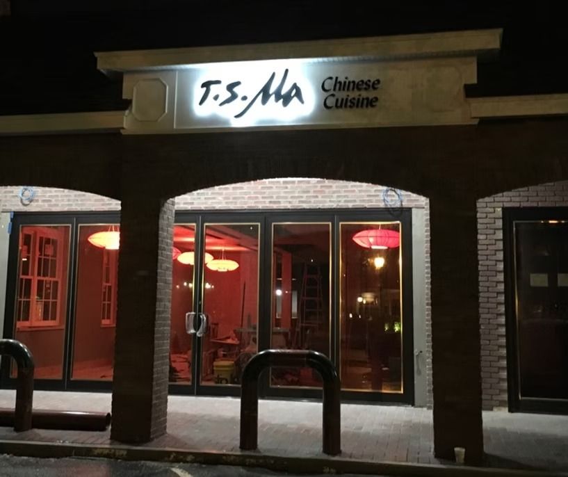A restaurant called t.s. ma is lit up at night