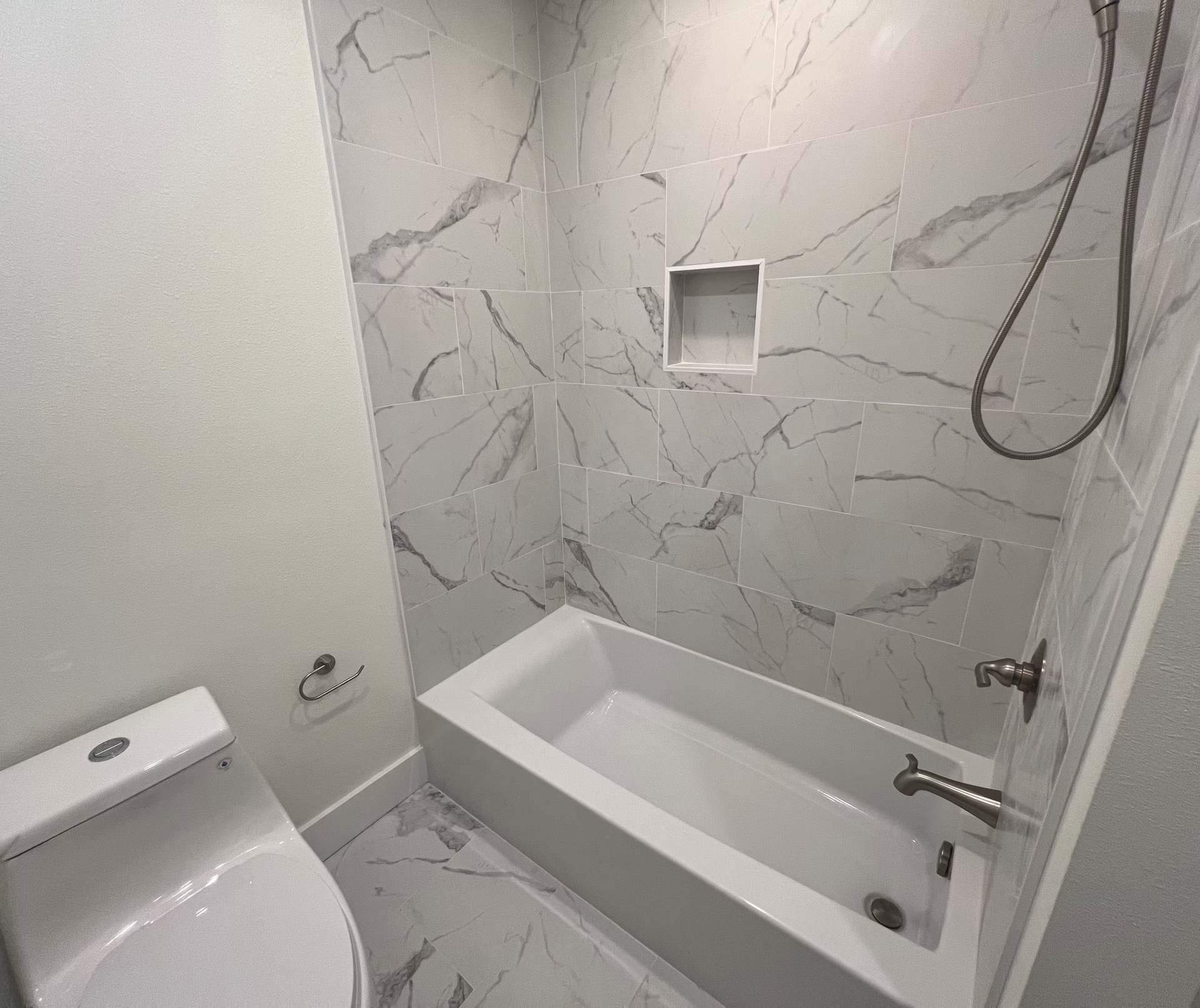 A bathroom with a bathtub , toilet and shower.