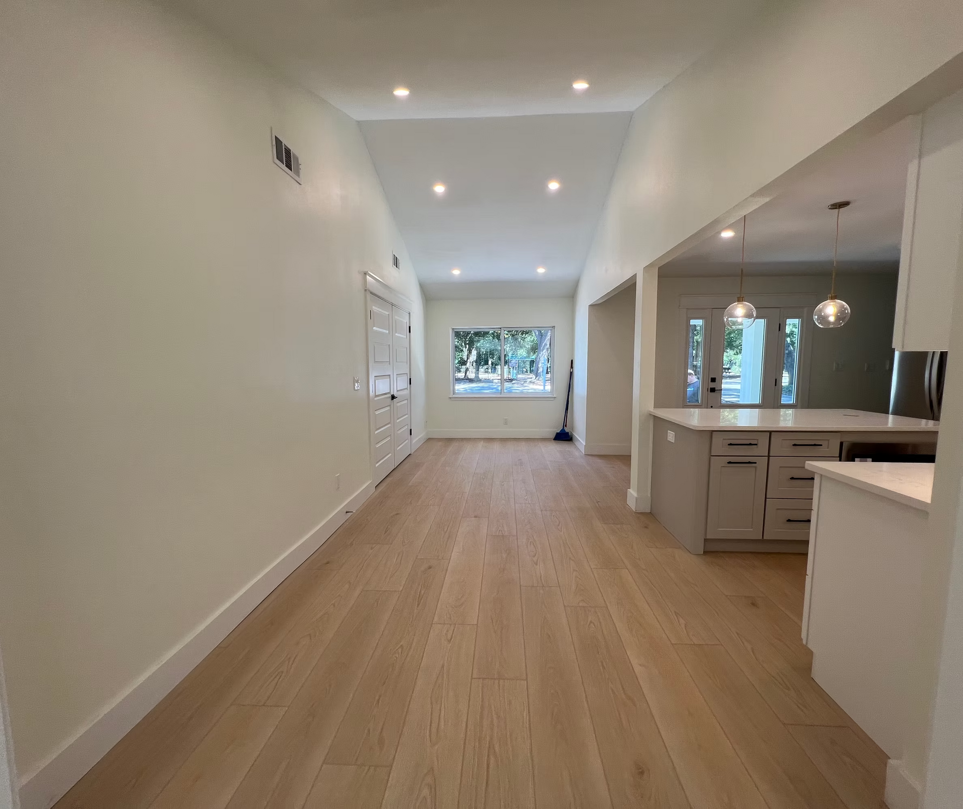 A large empty room with hardwood floors and white walls.