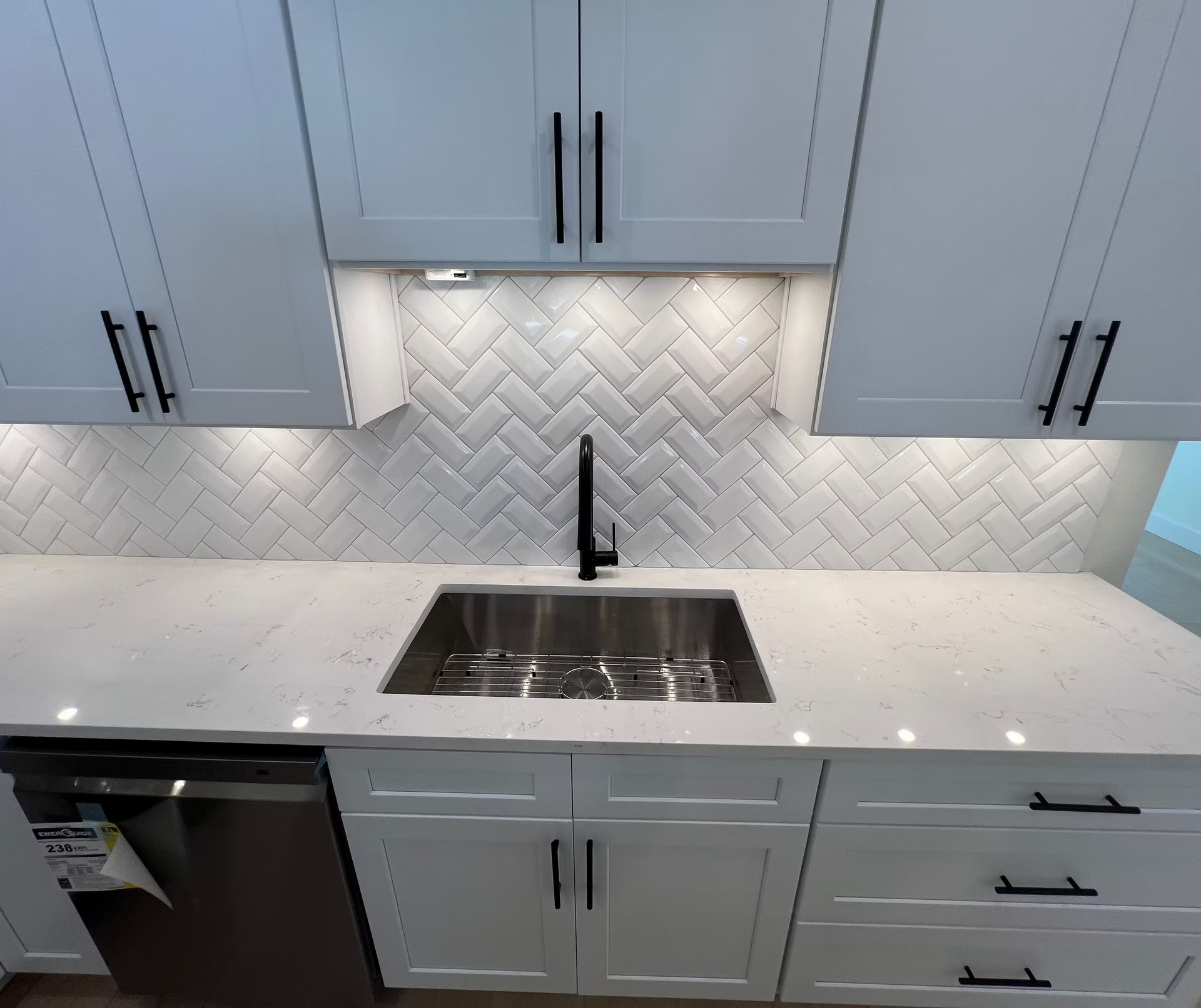 A kitchen with white cabinets and a stainless steel sink