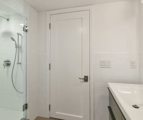 A bathroom with a shower , sink , and door.