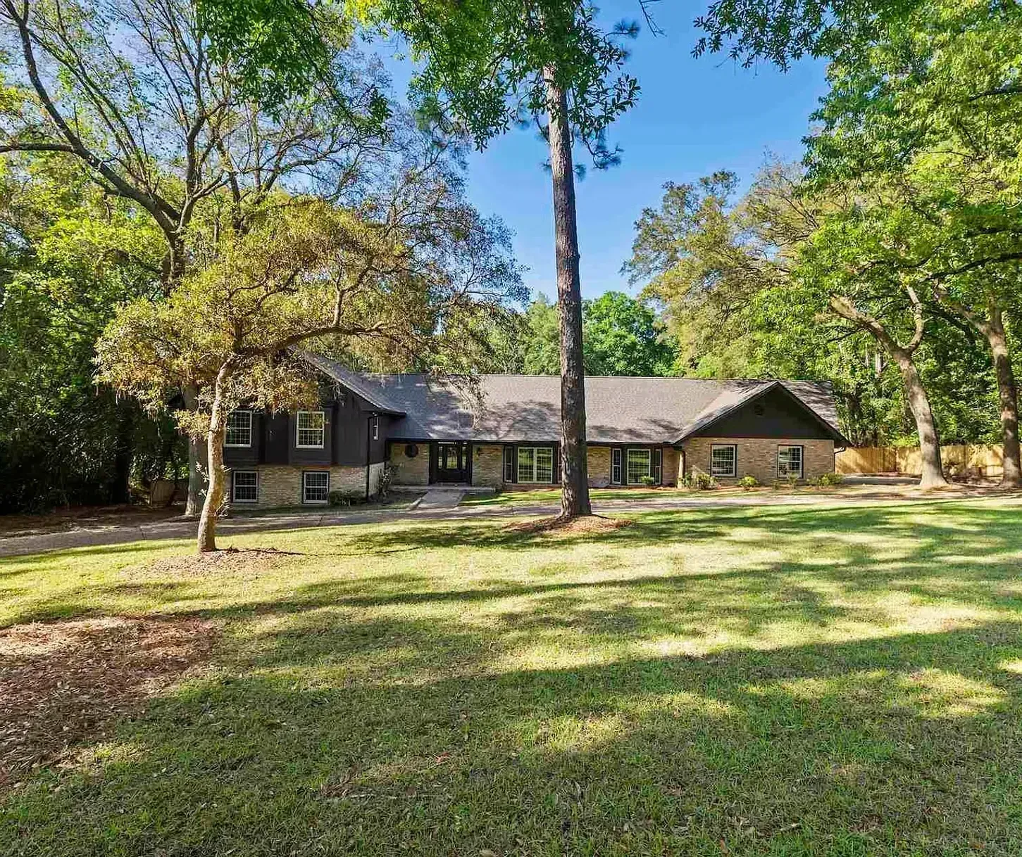 A large house with a large lawn in front of it surrounded by trees.