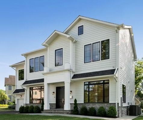 A white house with black windows and a blue sky in the background.