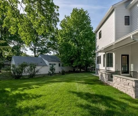 A white house with a large lawn in front of it.