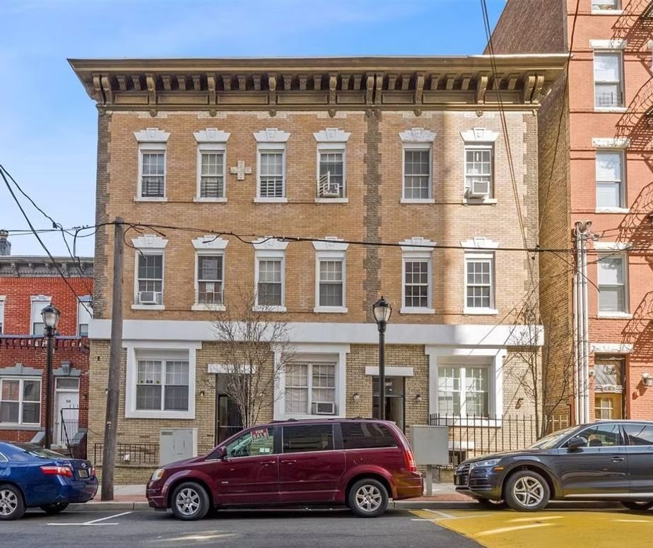 A red van is parked in front of a large brick building.
