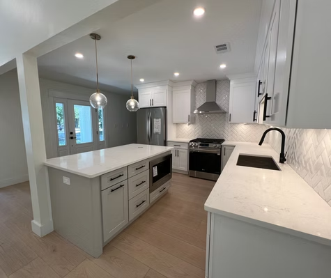 A kitchen with white cabinets , stainless steel appliances , and a large island.